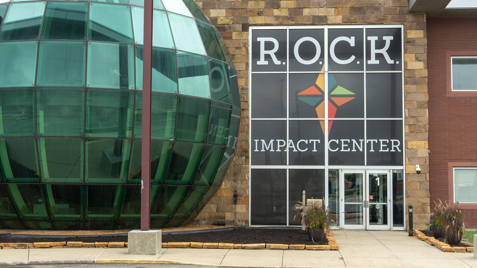 The ROCK Impact Center's front entrance, its name and star emblem on the glass above the doors, with the Globe Room's green glass dome alongside